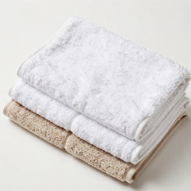 Bright clean home photography of neatly folded stacks of high-quality bath towels on a white shelf, even neutral daylight, crisp white and soft cream tones, sharp focus, 35mm