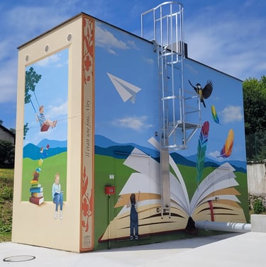 Fresque sur les façades d'un haut bâtiment. Un livre ouvert, des enfants jouent, un oiseau s'envole.