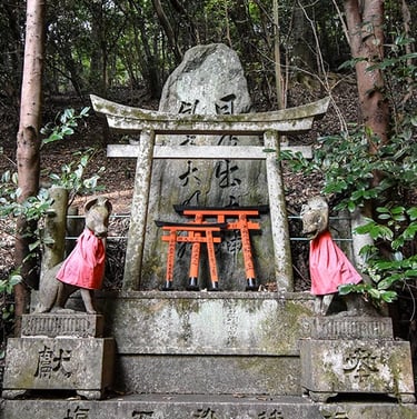 Petit sanctuaire dans la montagne avec des mini portes torii et deux kami renards sur les cotés