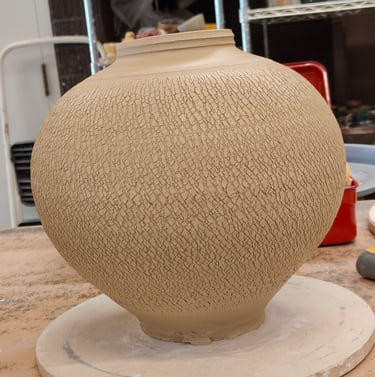wheel-thrown moon jar with sodium silicate crack pattern, waiting for trimming