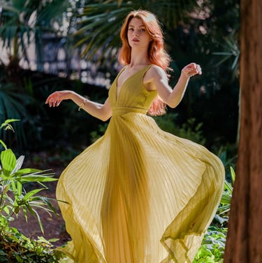 Ragazza in mezzo alla vegetazione con un abito dorato svolazzante