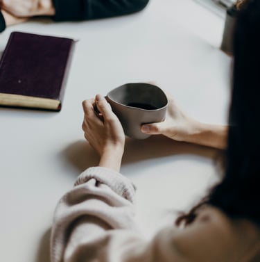 a person holding a cup of coffee and a book
