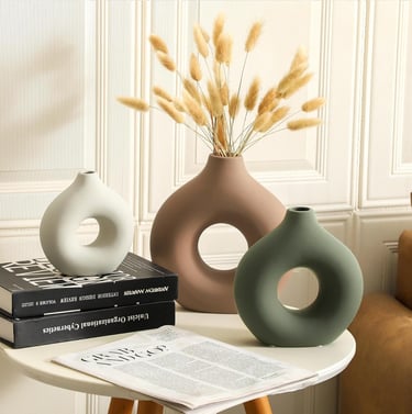 Set of three modern ceramic donut vases in white, brown, and green with dried pampas grass decor.