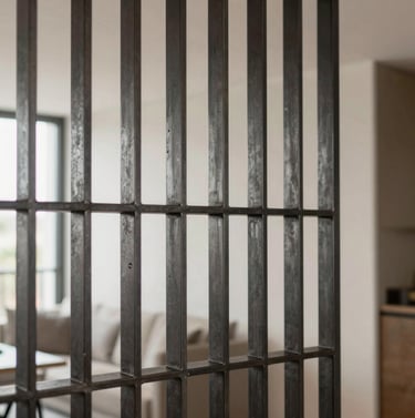 Side profile of a bespoke steel partition in a high-end apartment. The lighting highlights the matte finish of the deep charcoal metal and the crystal-clear glass panels, showcasing industrial elegance.