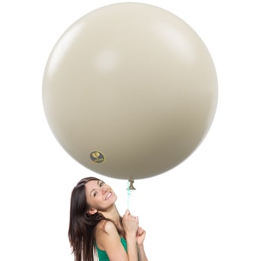 A smiling woman holds a giant 36-inch sand white latex balloon for party decorations.