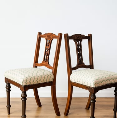 Pair of antique wooden dining chairs with cushioned seats