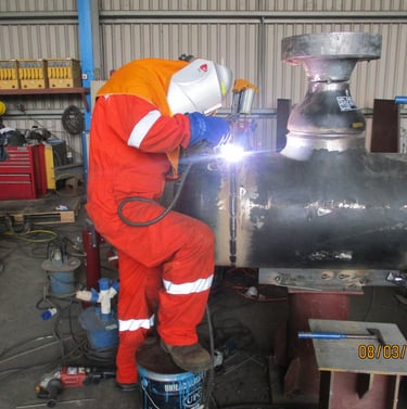 Professional weldere  performing industrial pipe welding in a workshop.