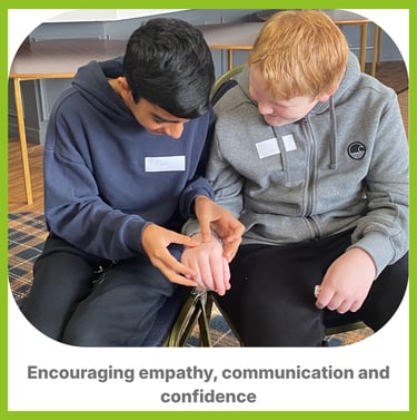 Two boys, one assessing the others hand. Learning confident care for someone who is ill of injured