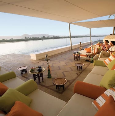Couple relaxing at Hilton Luxor Resort & Spa terrace with outdoor sofas and shisha pipes.