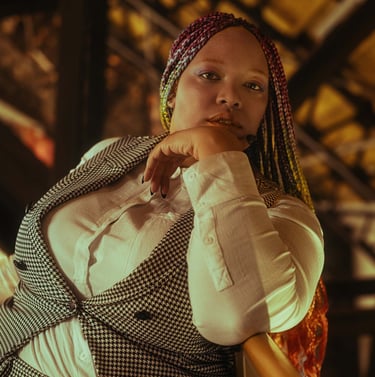 A picture of Lamia, a Black person wearing a gingham vest and white button up shirt