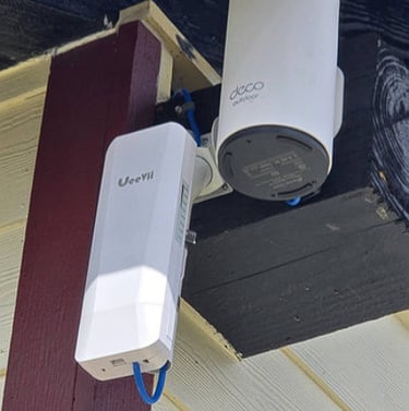 TP-Link Deco outdoor mesh WiFi node and UeeVii wireless bridge mounted on a house exterior.