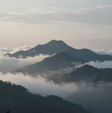 A cinematic landscape shot of a mountain peak piercing through a layer of low clouds, early morning light, muted #A0B0C0 tones and deep blue shadows, vast and epic composition, 4K film quality.