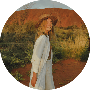 portrait of young woman in a hat standing in front of Uluru, Australia