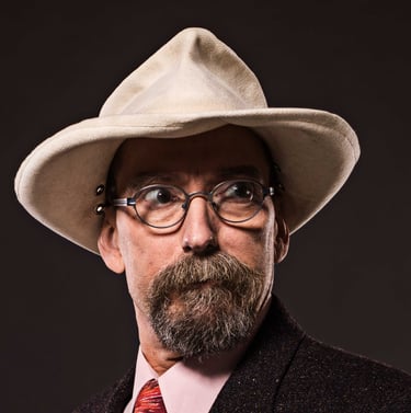 a man with a tan hat, a beard, and glasses