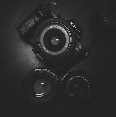 A black and white photo of a Sony digital camera with 3 Canon lenses.