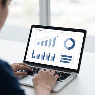 A professional consultant working on a clean laptop screen showing analytics charts in a bright, daylight-filled workspace, cool navy tones, high-contrast, shallow depth of field.