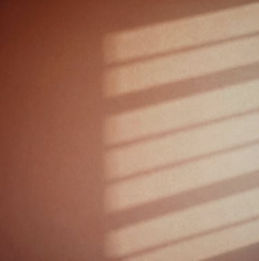 A conceptual, artistic photograph of soft light patterns reflecting off a studio wall. The colors blend from warm terracotta to soft sand, creating a dreamlike, sophisticated visual representation of music.