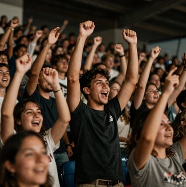 A dynamic shot of fans celebrating in the stands, capturing motion and joy. Authentic event photography with a focus on human connection, using warm #8C847E tones and deep #0D0D0D shadows.