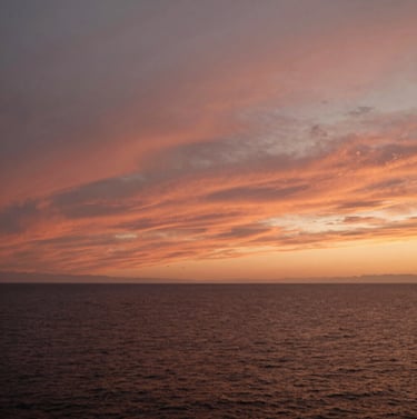 A wide cinematic landscape of a North American / US coast at sunset. The sky is filled with warm Terracotta and Soft Sand hues, evoking a sense of calm and storytelling.