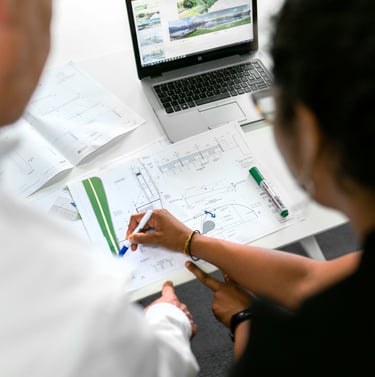 Civil engineers reviewing architectural blueprints and site plans with a laptop in an office.