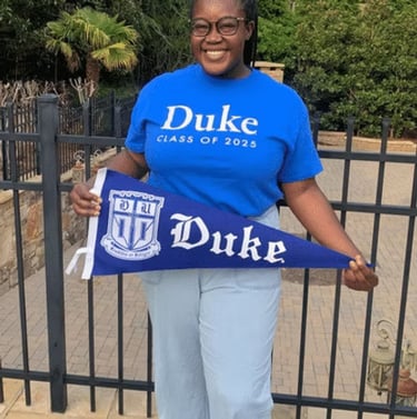 Black female posing with a Duke University banner
