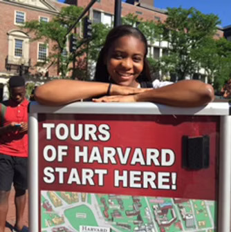Black Female posing with the Harvard Tour Sign