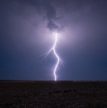 A breathtaking photography shot of a single bolt of lightning striking a distant horizon over a flat plain. The sky is a gradient of dark blue and deep slate. Clean, sharp focus on the electrical arc. International / Western scenery.