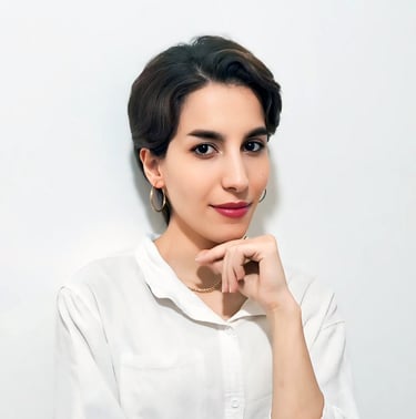 Portrait of a VISUALISE team member in a white shirt, gold necklace, and hoop earrings, against a plain white background.