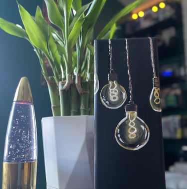 painting of lightbulbs on table with lava lamp and lucky bamboo plant