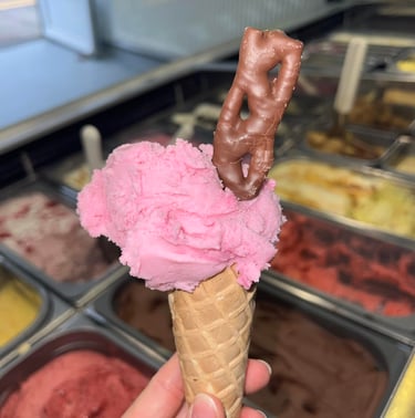 Single scoop in cone. Strawberry flavour with Curly Wurly. Ice cream display.