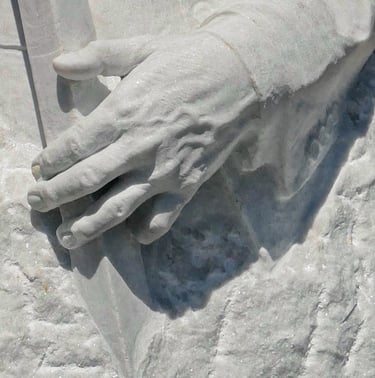 Detailed close-up of a hand carved from white marble, showing intricate veins and textures in the stone.