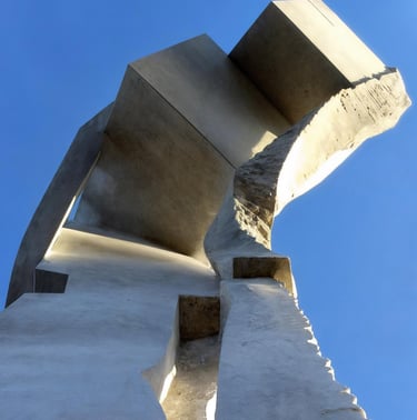  brutalist white marble sculpture with geometric shapes against a clear blue sky.