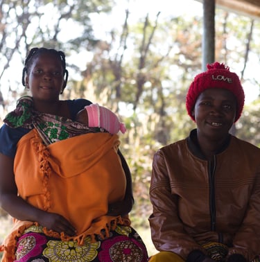 two women sitting on a bench in a outside a rural community centre in Ndola, Zambia