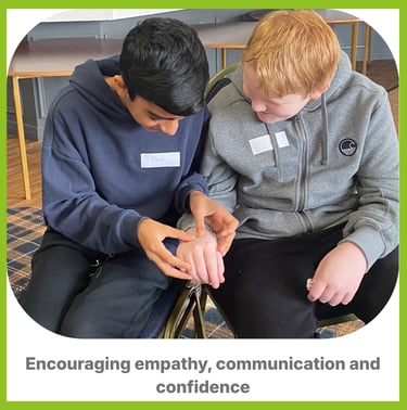 Two boys, one assessing the others hand. Learning confident care for someone who is ill of injured