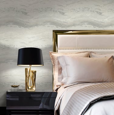 Elegant bedroom with marble textured wallpaper, gold table lamp, and luxury bedding.