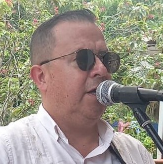 Vocalista masculino con una guayabera blanca y gafas de sol, cantando en un micrófono profesional al
