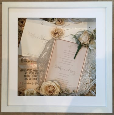 a photo of a memory box full of wedding items and preserved wedding bouquet flowers in a deep frame