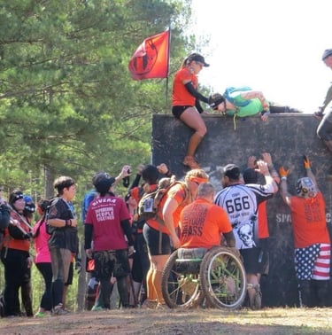 people helping other athletes over a wall at a spartan race