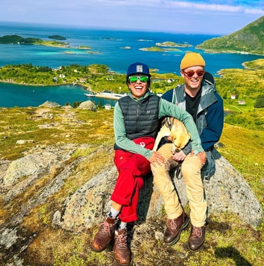 a man and woman sitting on a rock in the mountains of the Lofoten islands | Island hopping