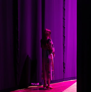 a woman standing in front of a purple curtain