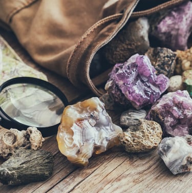 Piedras preciosas de amatista morada en bruto en una bolsa de lona, ​​y lupa