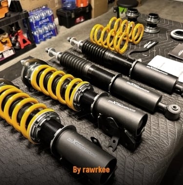 A set of four adjustable coilover suspension struts with yellow springs.