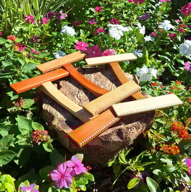 A collection of our hand looms. Three medium size hand looms of assorted woods in a flower garden.