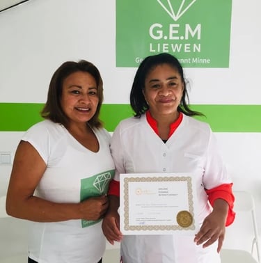 Deux femmes souriantes posant dans un centre de formation G.E.M. Liewen, l’une tenant un certificat