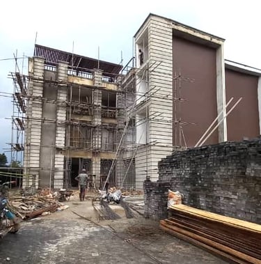 A modern commercial building under construction with metal scaffolding and stacked building materials.