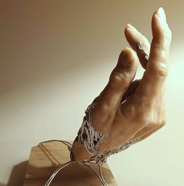 A sculpture of a single hand, part wire, part flesh coloured clay, with wire supports
