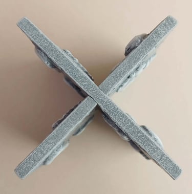 Two intersecting relief sculptures forming an X shape, and depicting three dimensional footprints.