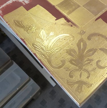 Détail de la pose de dorure à la feuille d'or pour le décor d'un échiquier.