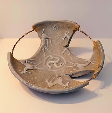 A fragmented bowl-like sculpture with embossed horse figures and symbols in rust/brown hues