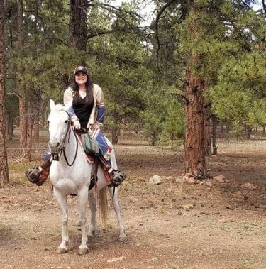 a dog and two horses are riding on a trail